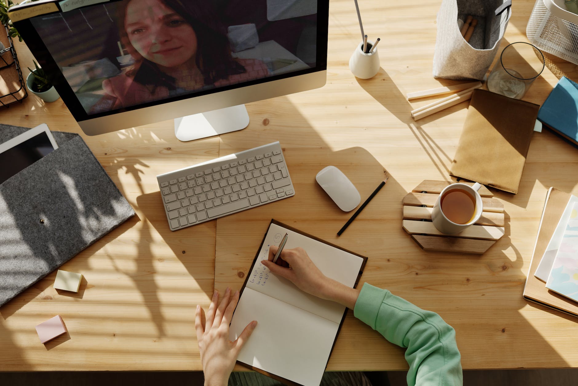 person writing on notebook while on a zoom call